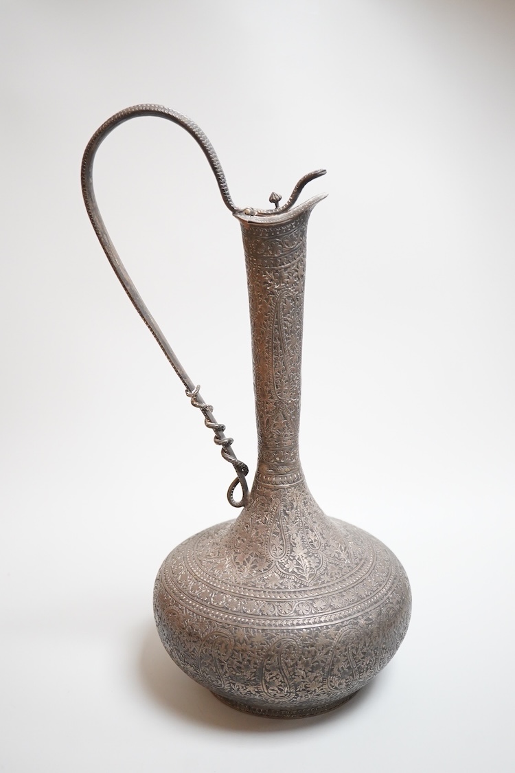 A late 19th century Indian white metal ewer, with extensive foliate decoration and cobra handle, height 30.3cm.